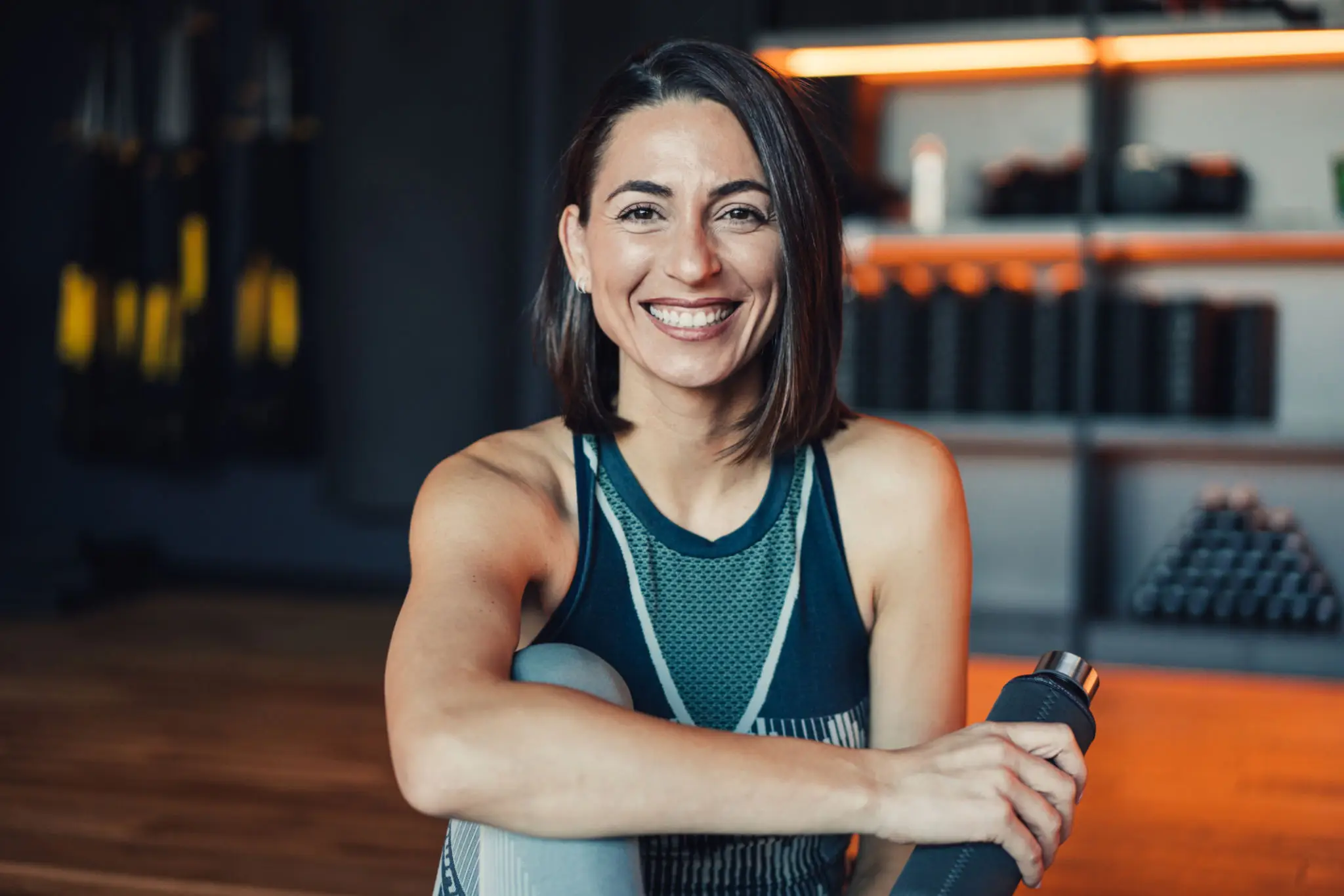 Smiling woman holding a water bottle indoors.