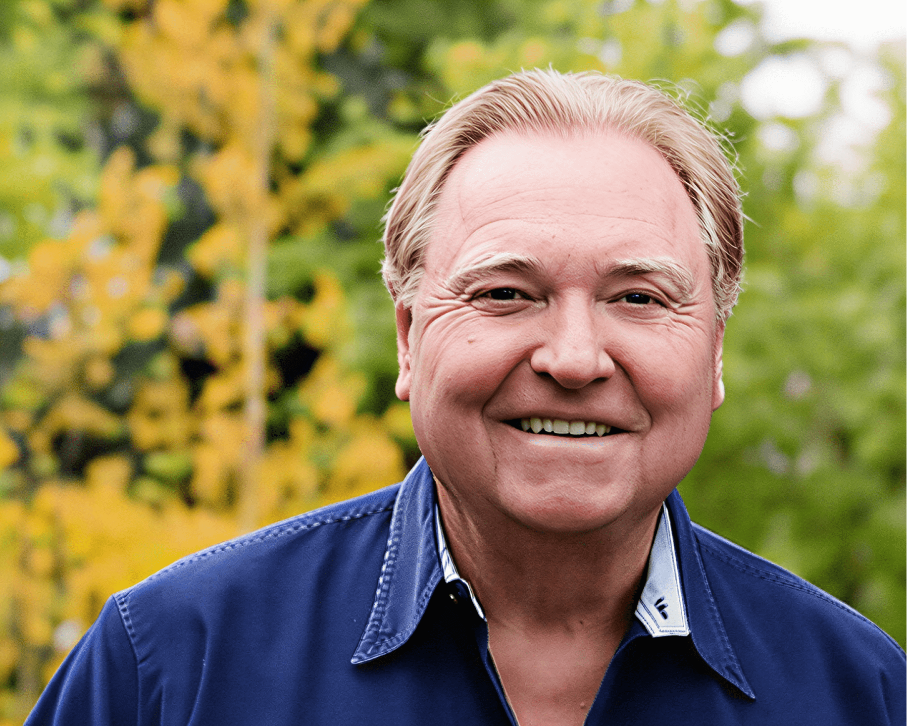 Man in blue shirt, nature backdrop.