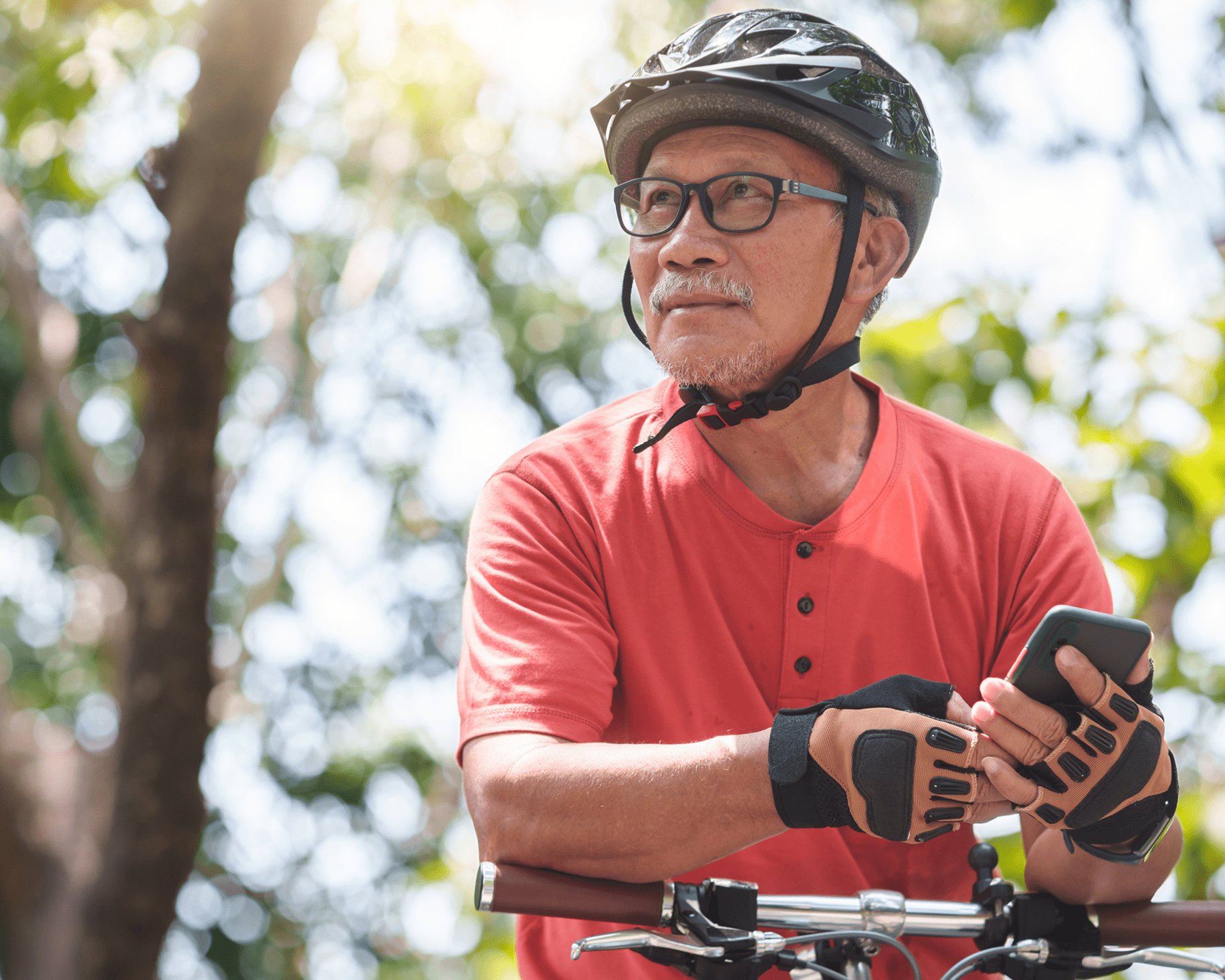 Senior cyclist holding phone outdoors