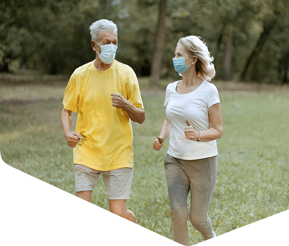 Elderly couple jogging with masks outdoors.
