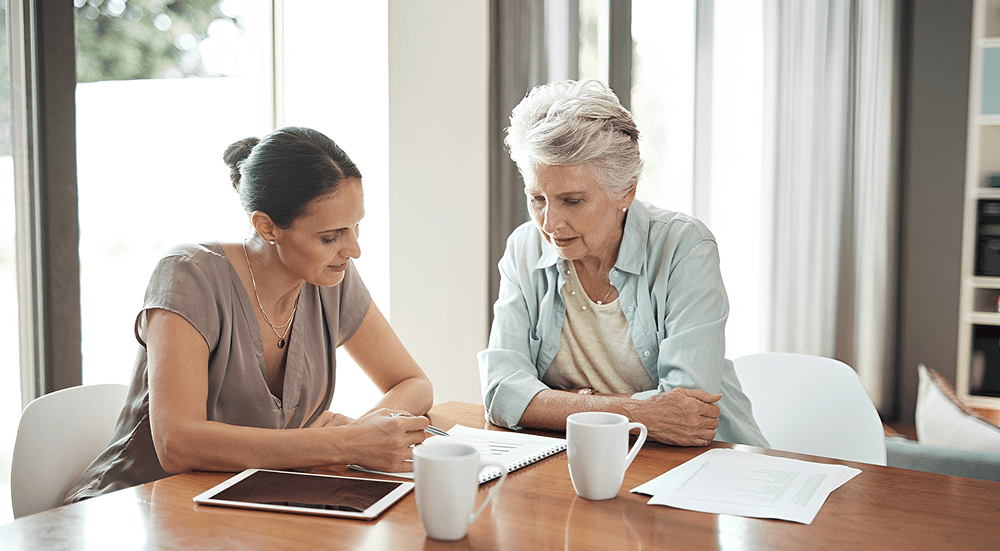 Two women discussing documents at table.