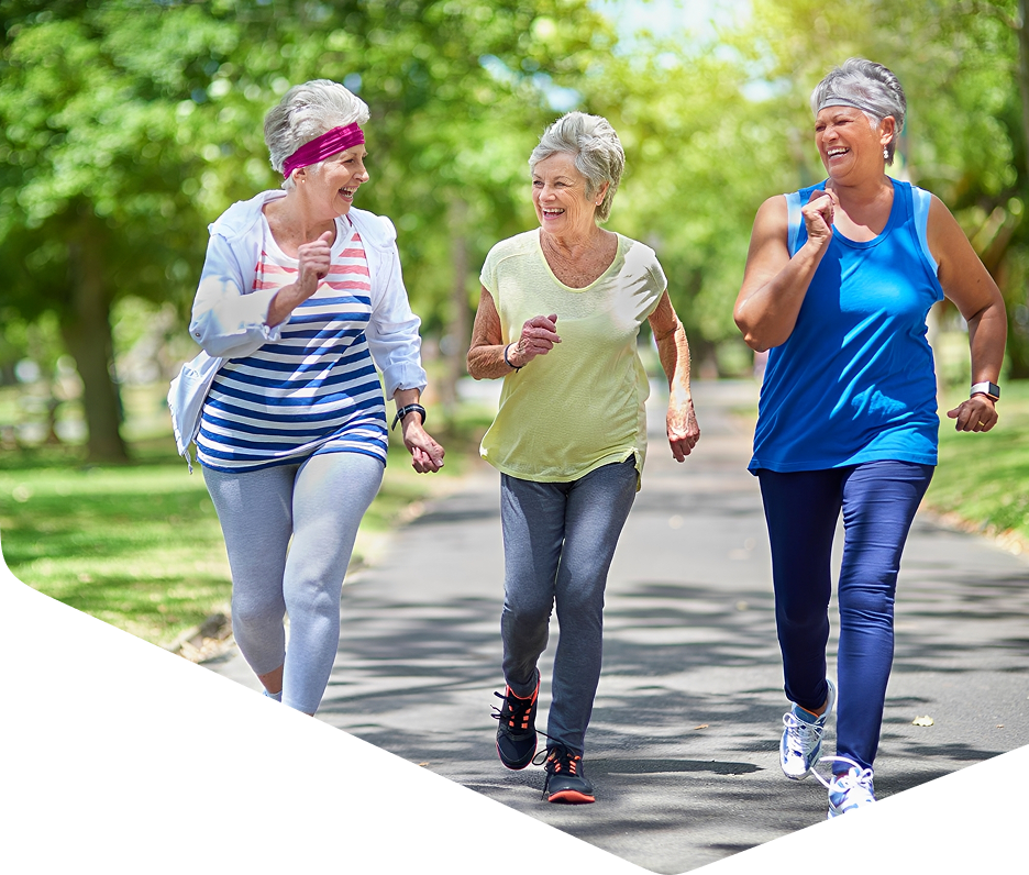 Three women jogging outdoors, smiling together.