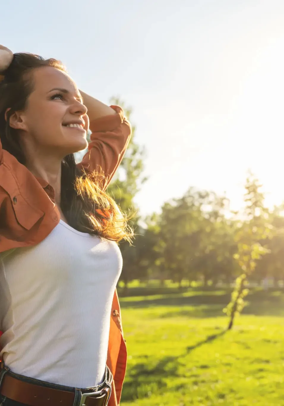 Woman enjoying sunlight in a green park.