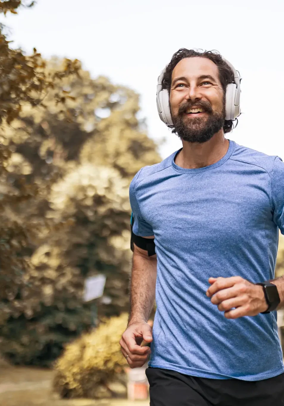 Man jogging with headphones in park.