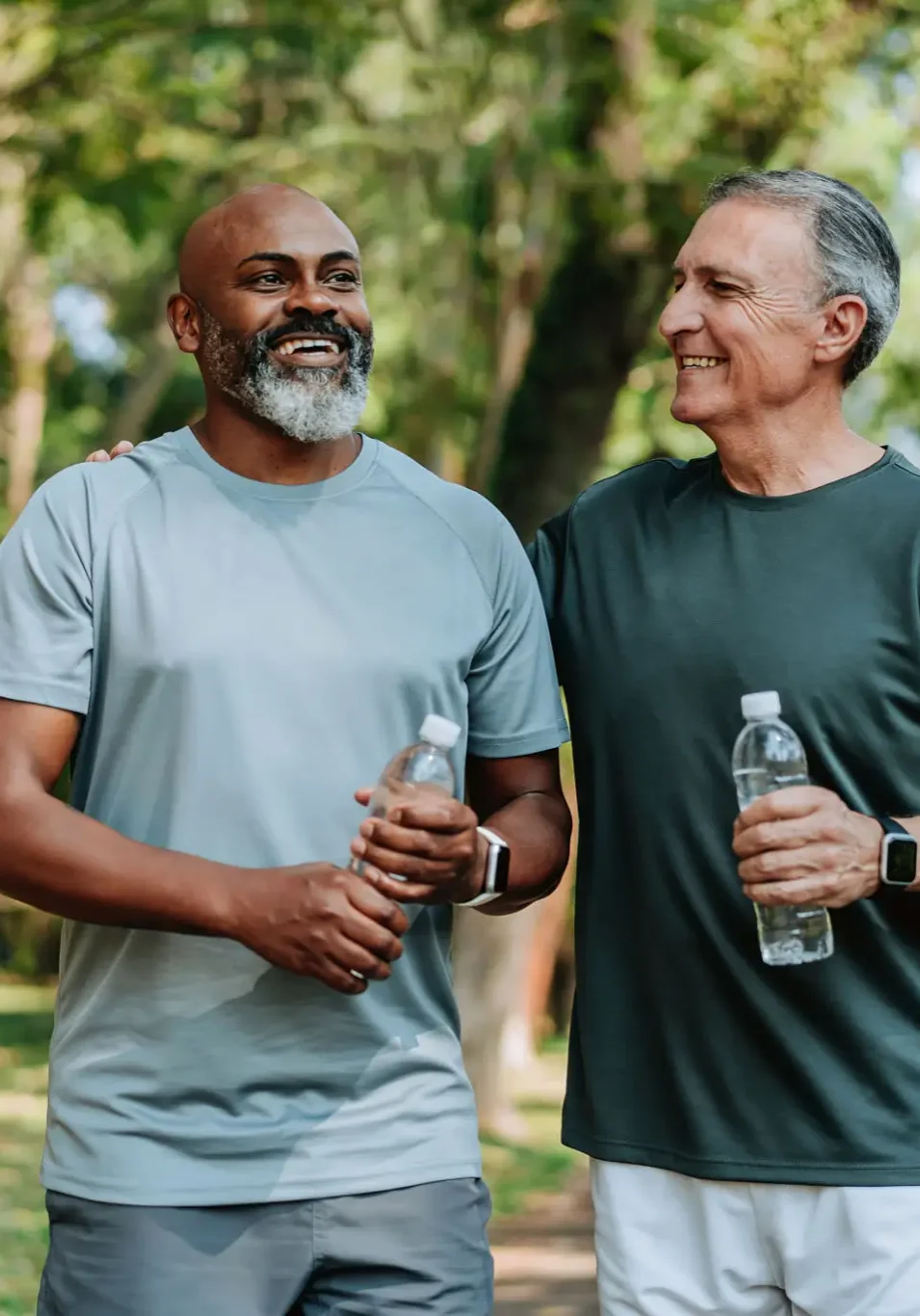 Two men walking with water bottles outdoors.